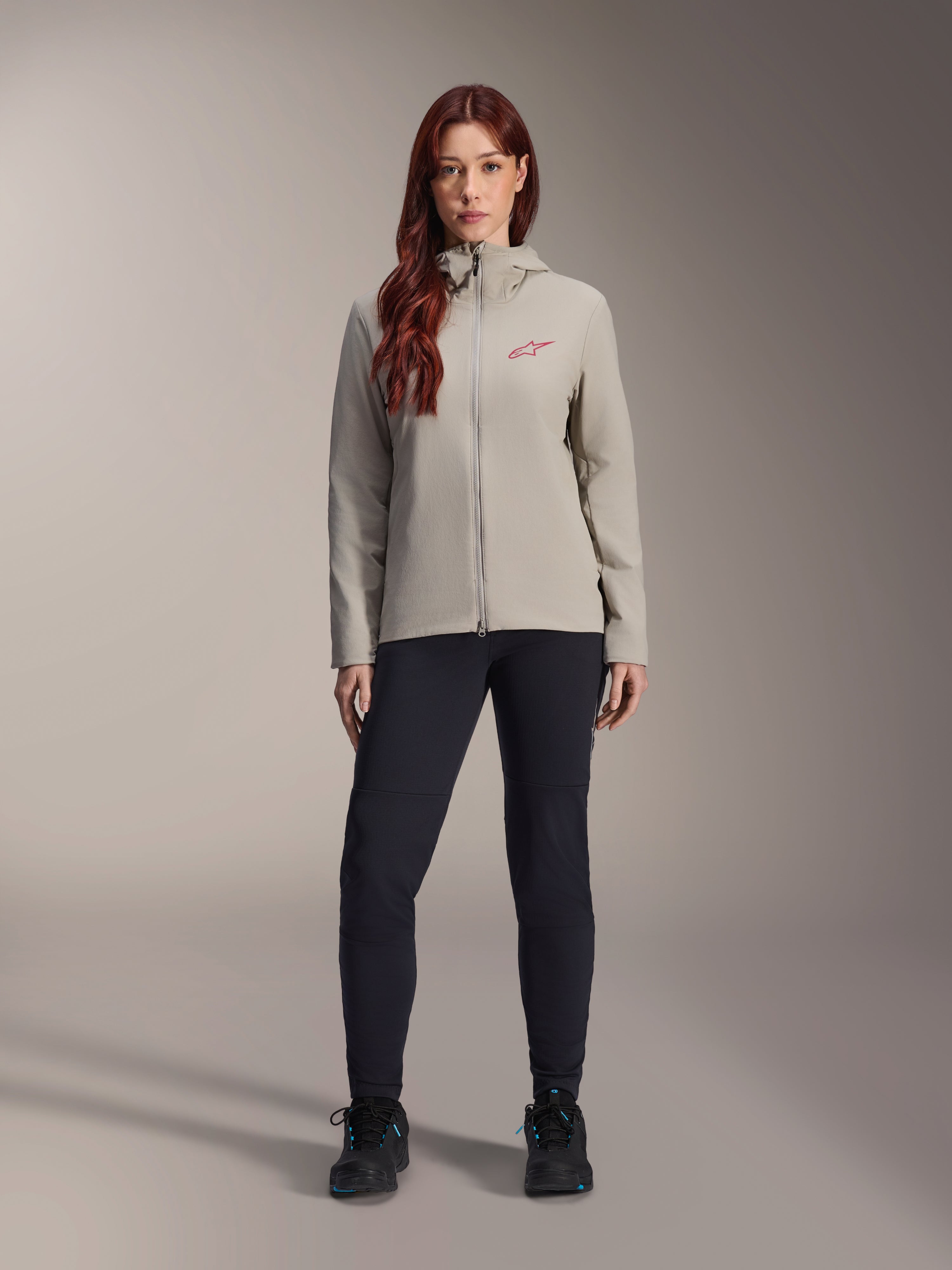 Alpinestars Woman Stella A-Dura Thermal Jacket, Mountain Bike Jacket, Titanium gray, worn with black technical pants and black footwear, featuring a fleece-lined hood and red chest logo, designed for cold-weather riding