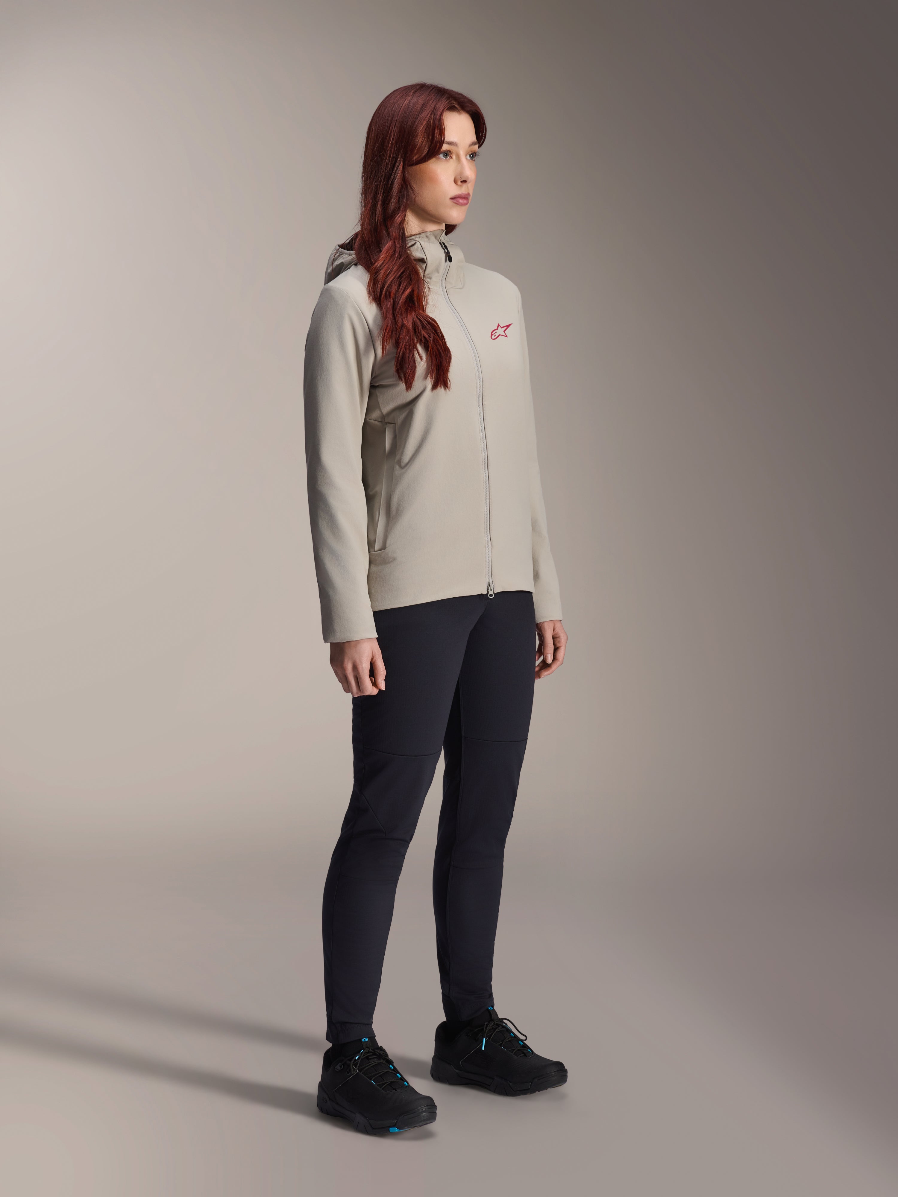 Alpinestars Stella A-Dura Thermal Jacket, Titanium gray, women's thermal cycling jacket with a red star logo on the chest, worn with black technical pants and black mountain bike shoes, studio shot for outdoor cycling apparel