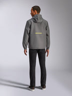 Casaco Corta-vento Alpinestars Speeder Chromium, cinzento escuro e amarelo de alta visibilidade, vista traseira com logótipo amarelo Alpinestars no centro, corta-vento leve com capuz e punhos elásticos, streetwear casual inspirado no desporto motorizado