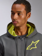 Casaco Corta-vento Alpinestars Speeder Chromium, cinzento antracite com detalhes em amarelo de alta visibilidade, logótipo de estrela amarela no peito, forro do capuz em malha a condizer, corta-vento casual leve