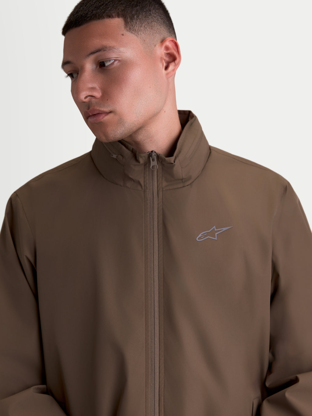 Alpinestars casaco Overhaul Racer, casaco de sportswear leve para homem, castanho, design de inspiração motorsport com gola alta, compartimento para capuz oculto e logótipo Astars em impressão HD no peito.