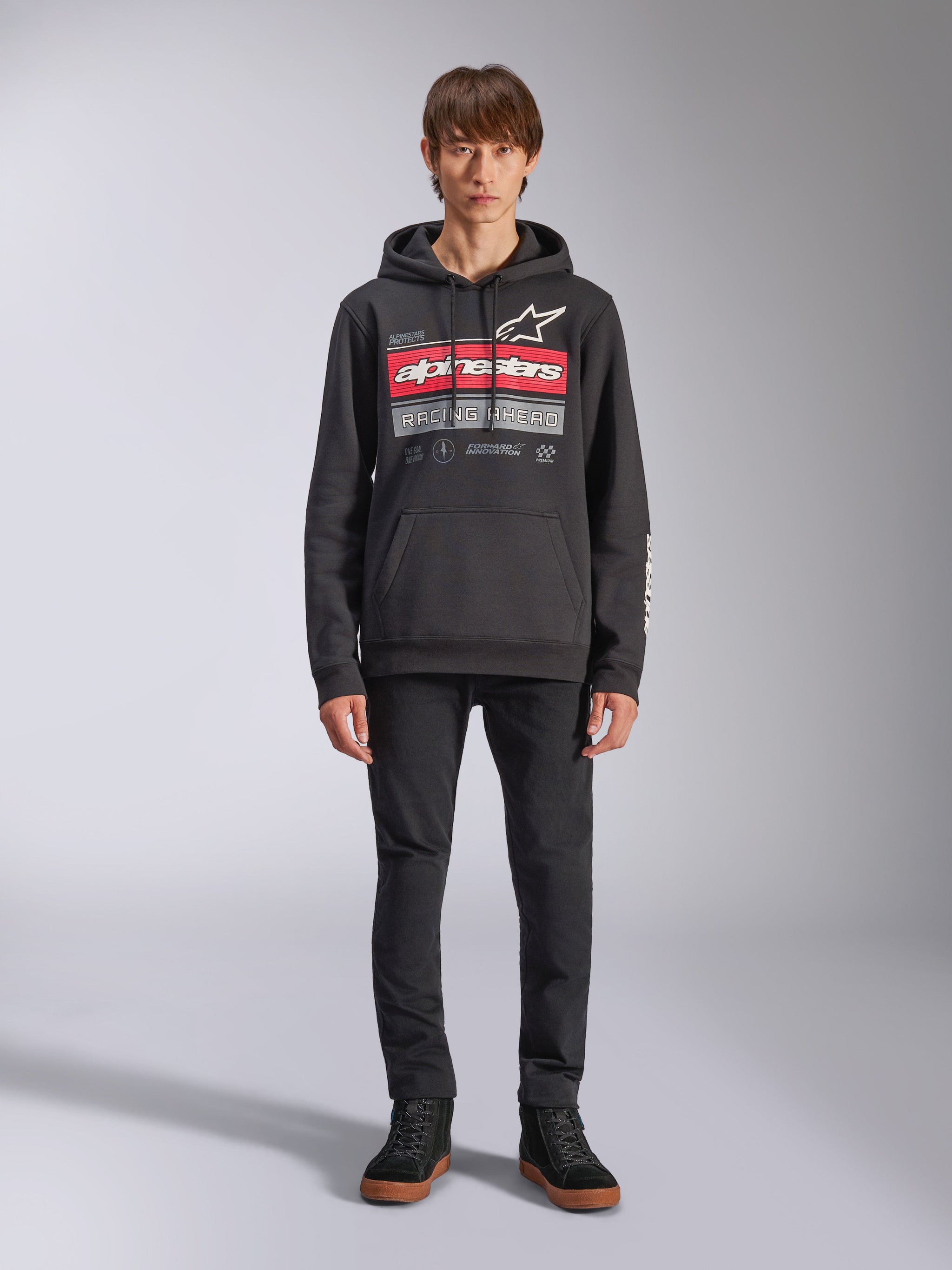 Alpinestars Harken Hoodie, hoodie preto, gráfico arrojado no peito com riscas vermelhas e o texto 'Racing Ahead', logótipo Astars branco, bolso canguru, capuz com cordão, streetwear casual inspirado no desporto motorizado
