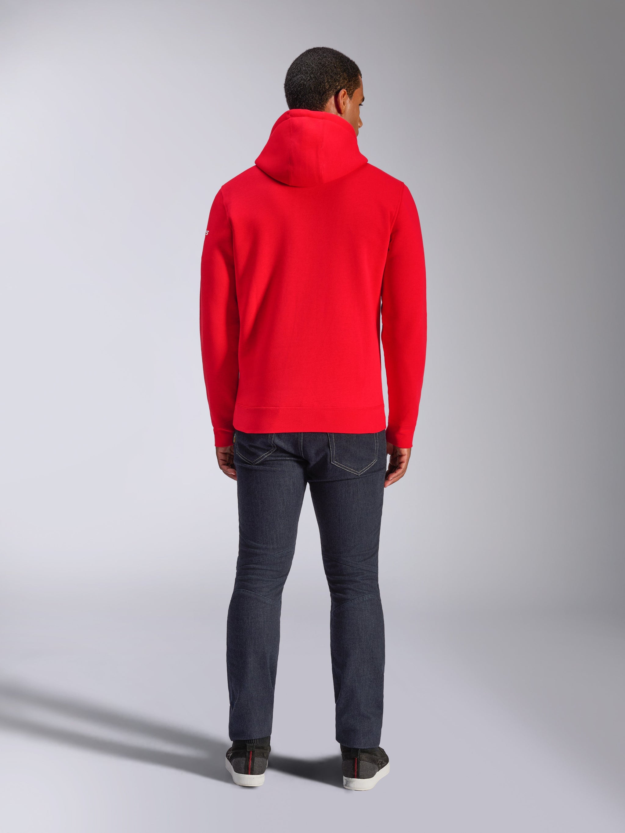 Alpinestars Frontal Hoodie, hoodie de lã vermelho, vista traseira, estilo casual urbano, usado com calças de ganga escuras e sapatilhas, inclui capuz e bainha canelada