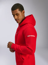 Alpinestars Frontal Hoodie, vermelho, hoodie em fleece tipo pullover usado por um modelo, com o logótipo Alpinestars branco na manga, logótipo frontal, bolso canguru e capuz com cordão, design casual inspirado no desporto motorizado