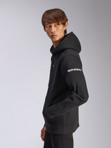 Alpinestars Frontal Hoodie, black pullover fleece, model wearing with side profile view, white alpinestars wordmark on sleeve, kangaroo pocket, casual motorsport-inspired streetwear