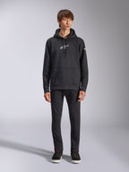 Alpinestars Frontal Hoodie, hoodie de lã preto, logótipo Alpinestars branco no peito e na manga, bolso canguru, capuz com cordão, usado com calças pretas, design casual inspirado no desporto motorizado
