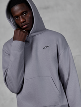 Alpinestars Essentials Ageless Hoodie, Silver, modelo masculino a usar o hoodie com o capuz levantado, pequeno logótipo Alpinestars preto no peito, bolso canguru, punhos canelados, estilo casual streetwear