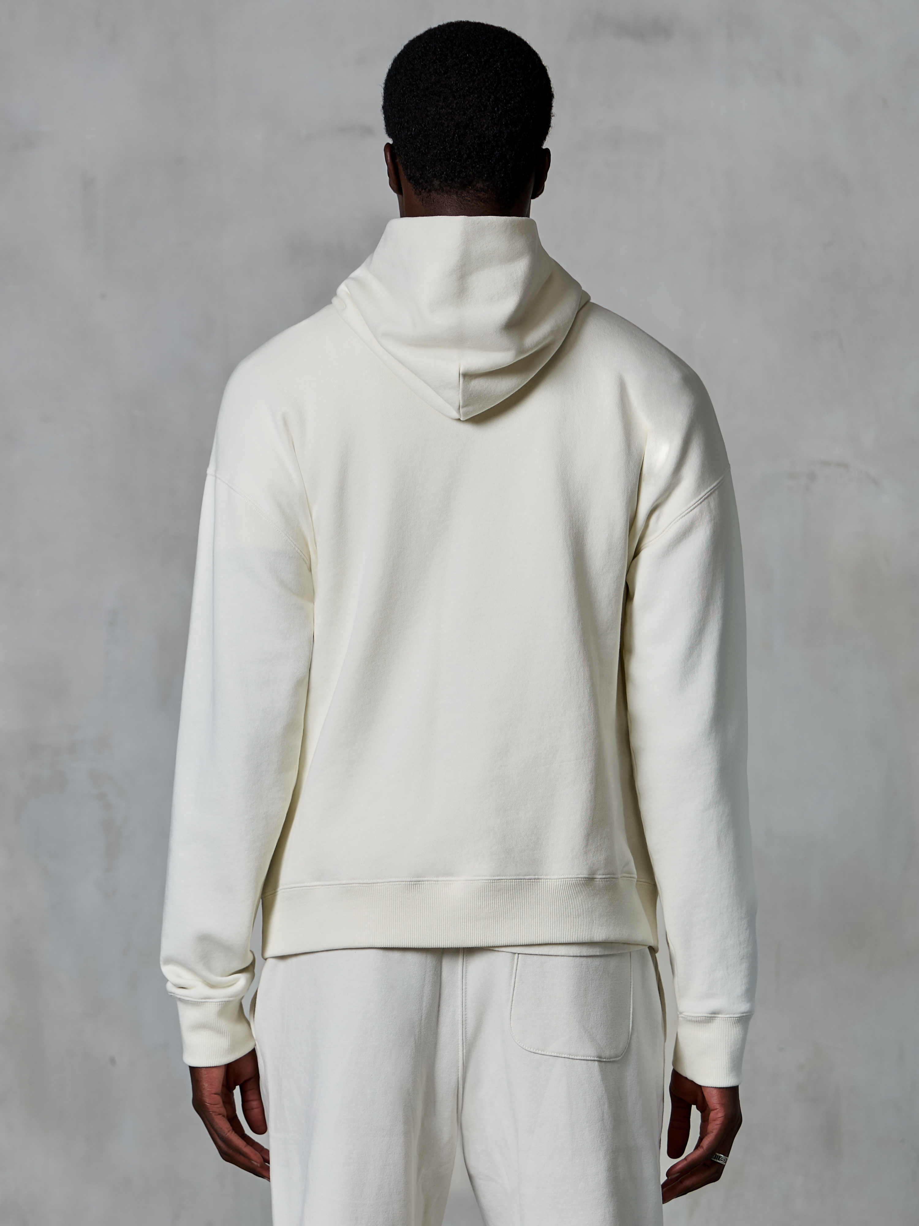 Hoodie Alpinestars Essentials Ageless, hoodie pullover off-white, vista de costas no modelo, design limpo e minimalista, calças casuais a condizer, corte relaxado para conforto diário