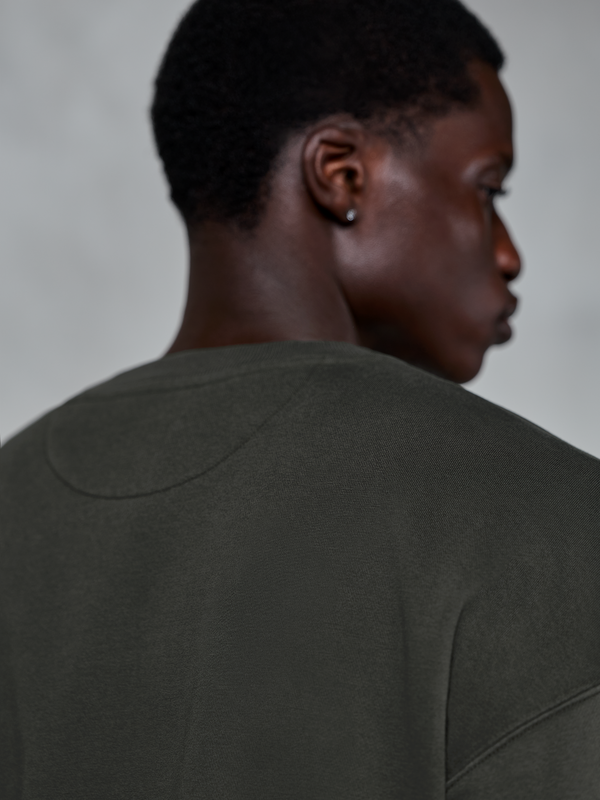 Alpinestars Essentials Ageless Crew, sweatshirt premium de gola redonda em Off Black, vista em grande plano da zona posterior da gola e ombros, textura de fleece compacto com lavagem de pedra, streetwear casual inspirado no desporto motorizado