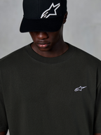 Alpinestars Essentials Ageless SS Tee, Short Sleeve T-Shirt, Off Black, featuring a small white Alpinestars logo on the chest, worn with a black logo baseball cap, casual motorsport streetwear style