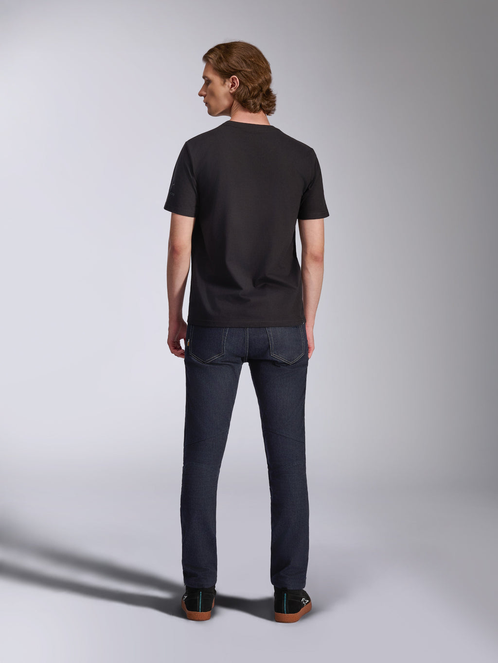 Alpinestars Global CSF Tee, t-shirt de manga curta em preto, vista traseira de modelo masculino a usar a t-shirt com calças de ganga escuras, streetwear casual inspirado no desporto motorizado