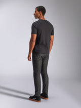 Alpinestars Tech Boot CSF Tee, t-shirt de manga curta, preta, vista traseira no modelo, usada com calças de ganga cinzento escuro e sapatilhas pretas, estilo casual motorsport streetwear