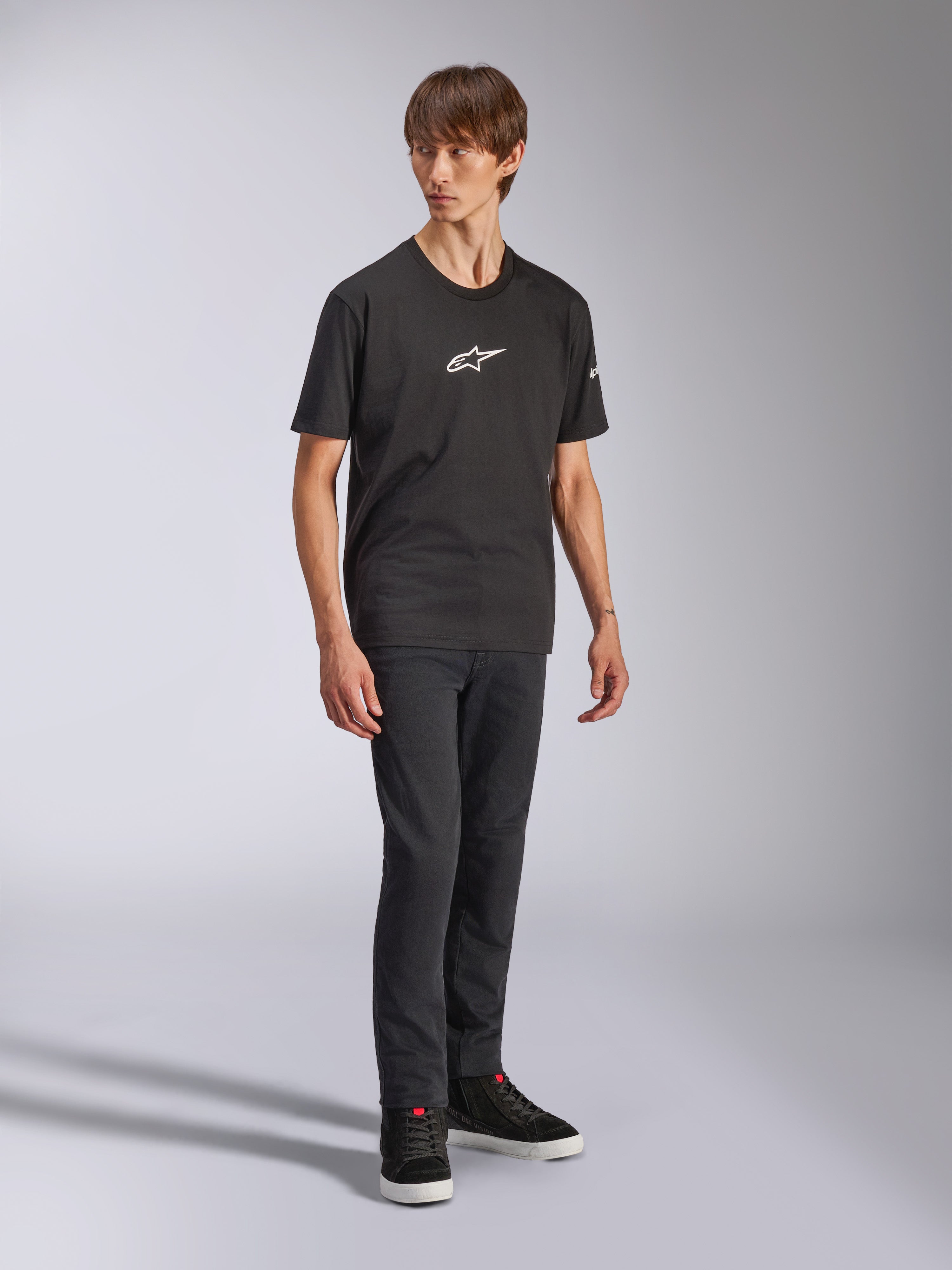 Alpinestars Frontal CSF Tee, t-shirt de manga curta, preta, logótipo Astars branco no peito, vestida por um modelo com calças de ganga escuras e sapatilhas pretas, streetwear casual de performance