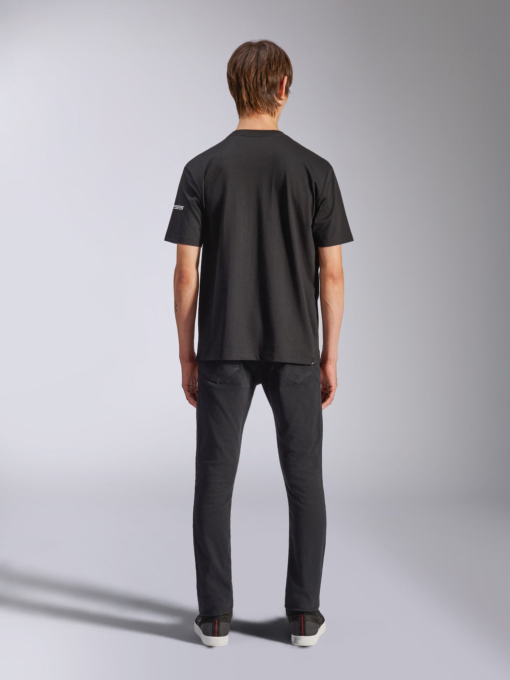 Alpinestars Frontal CSF Tee, t-shirt de manga curta, preta, vista traseira de modelo a usar calças de ganga pretas, streetwear casual de performance com detalhe de pequeno logótipo branco na manga