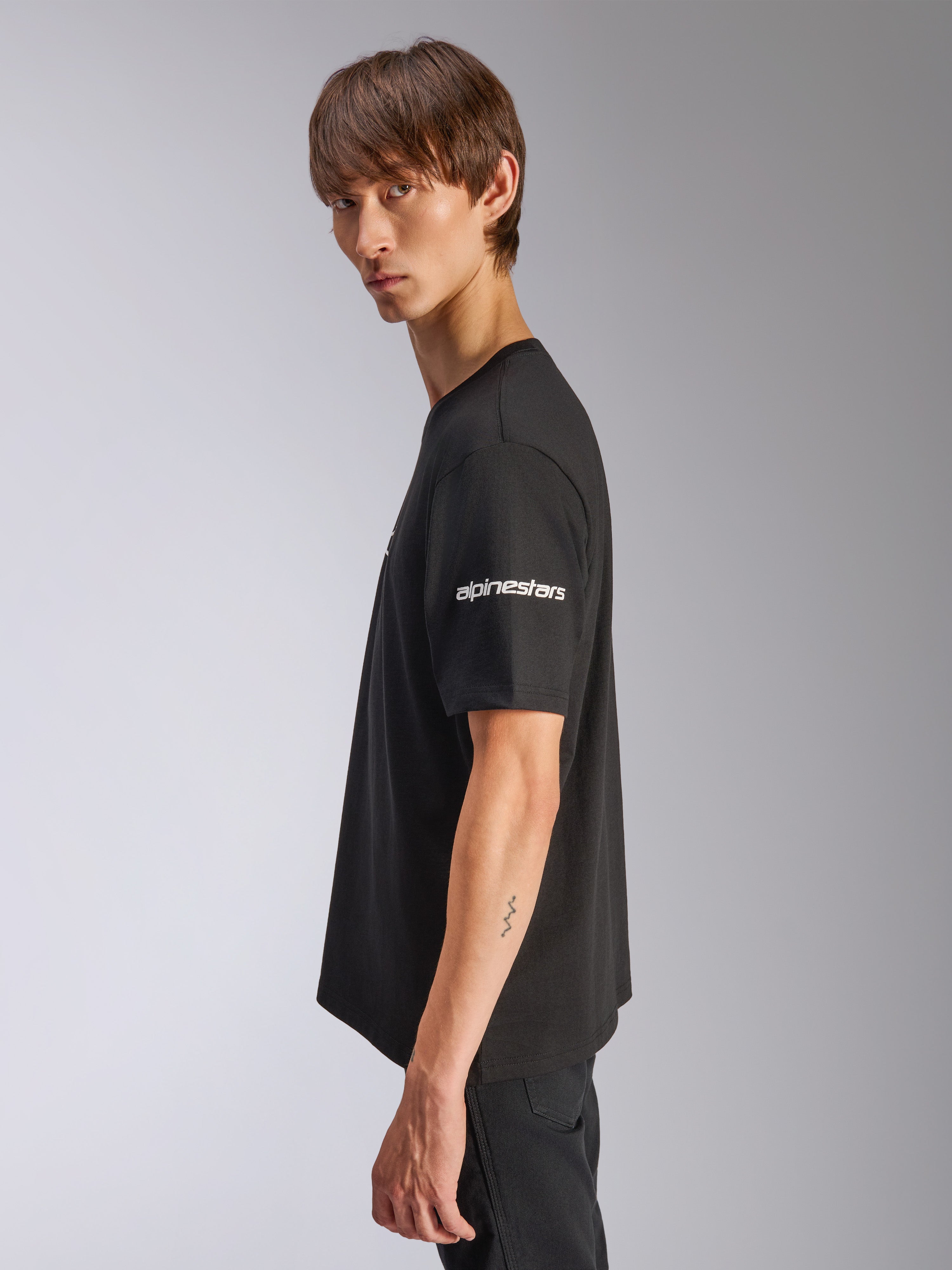 Alpinestars Frontal CSF Tee, t-shirt de manga curta, preta, logótipo Alpinestars branco na manga, vestida por modelo em vista de perfil, streetwear casual de performance motorsport