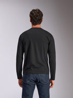 Alpinestars Trackside CSF Tee, t-shirt de manga comprida, preta, vista traseira, usada com calças de ganga azul-escuro, streetwear casual inspirado no desporto motorizado