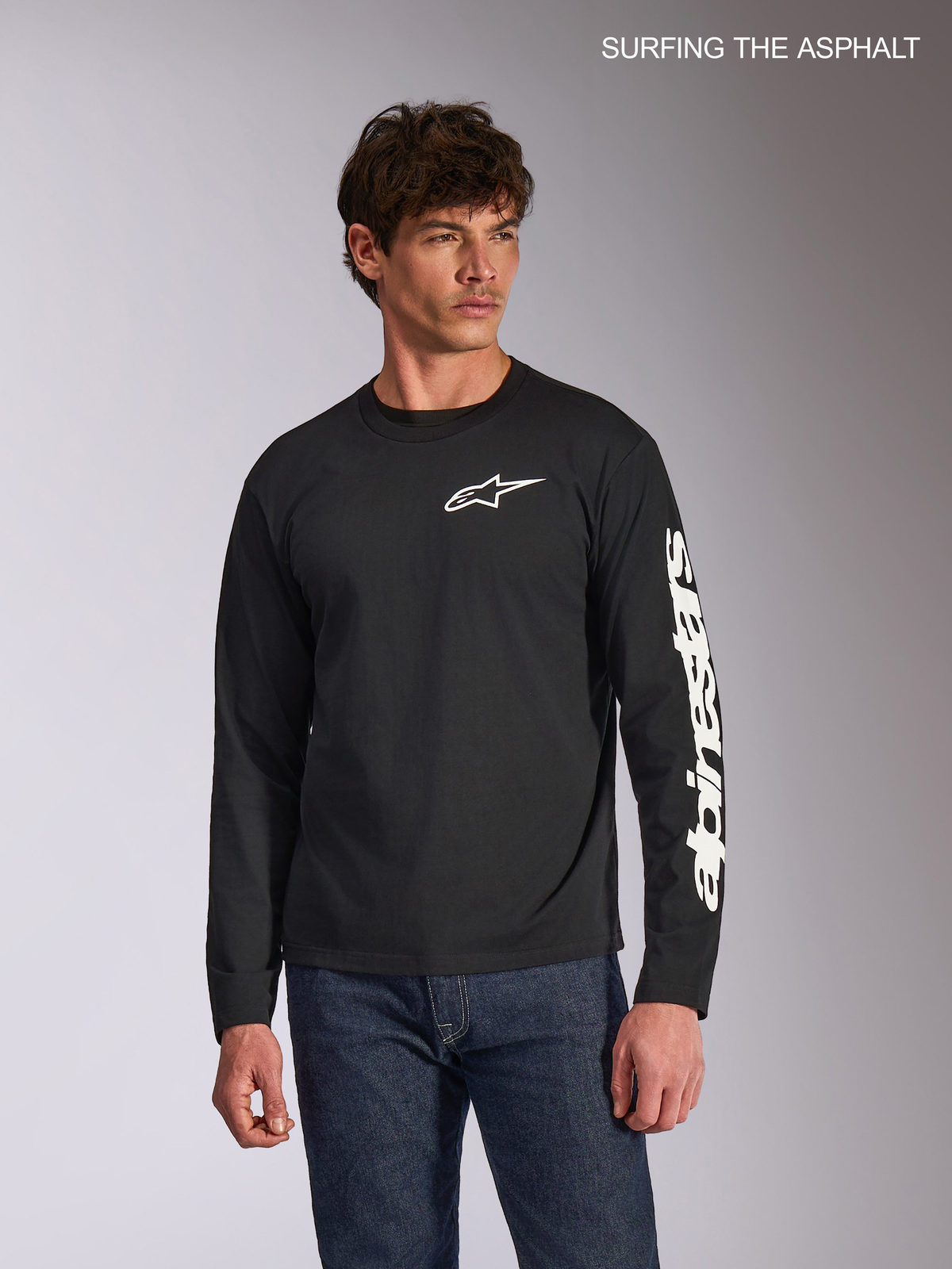 Alpinestars Trackside CSF T-shirt de manga comprida para homem, preta, com logótipo Ride 4.0 branco à frente e branding impresso na manga, num modelo com calças de ganga