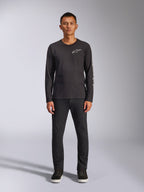 Alpinestars Trackside CSF Tee, t-shirt de manga comprida, preta, logótipo Alpinestars branco no peito e grafismo da marca na manga, usada com calças e sapatilhas pretas, streetwear casual inspirado no desporto motorizado