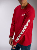 Alpinestars Trackside CSF Tee, t-shirt de manga comprida, vermelha, logótipo Alpinestars branco no peito e logótipo nominativo em destaque na manga, streetwear casual de desportos motorizados usada com calças de ganga azuis