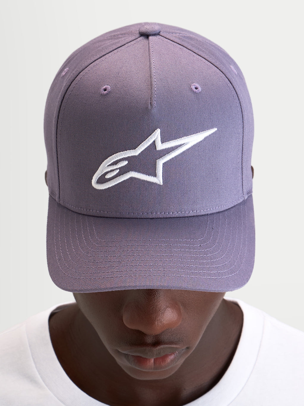 Alpinestars Ageless Snapback Hat, casual sportswear cap in dusty purple and white, featuring a curved bill, structured crown, and embroidered 3D Astars logo on the front, worn by a model