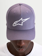 Alpinestars Ageless Snapback Hat, casual sportswear cap in dusty purple and white, featuring a curved bill, structured crown, and embroidered 3D Astars logo on the front, worn by a model