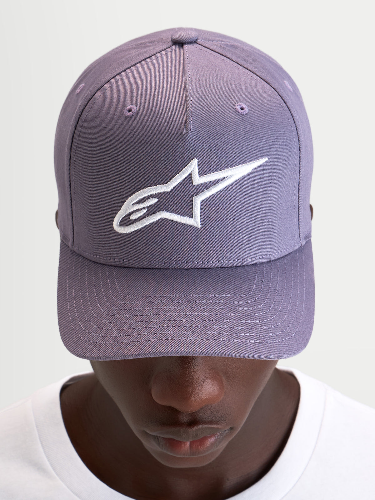 Alpinestars Ageless Snapback Hat, casual sportswear cap in dusty purple and white, featuring a curved bill, structured crown, and embroidered 3D Astars logo on the front, worn by a model