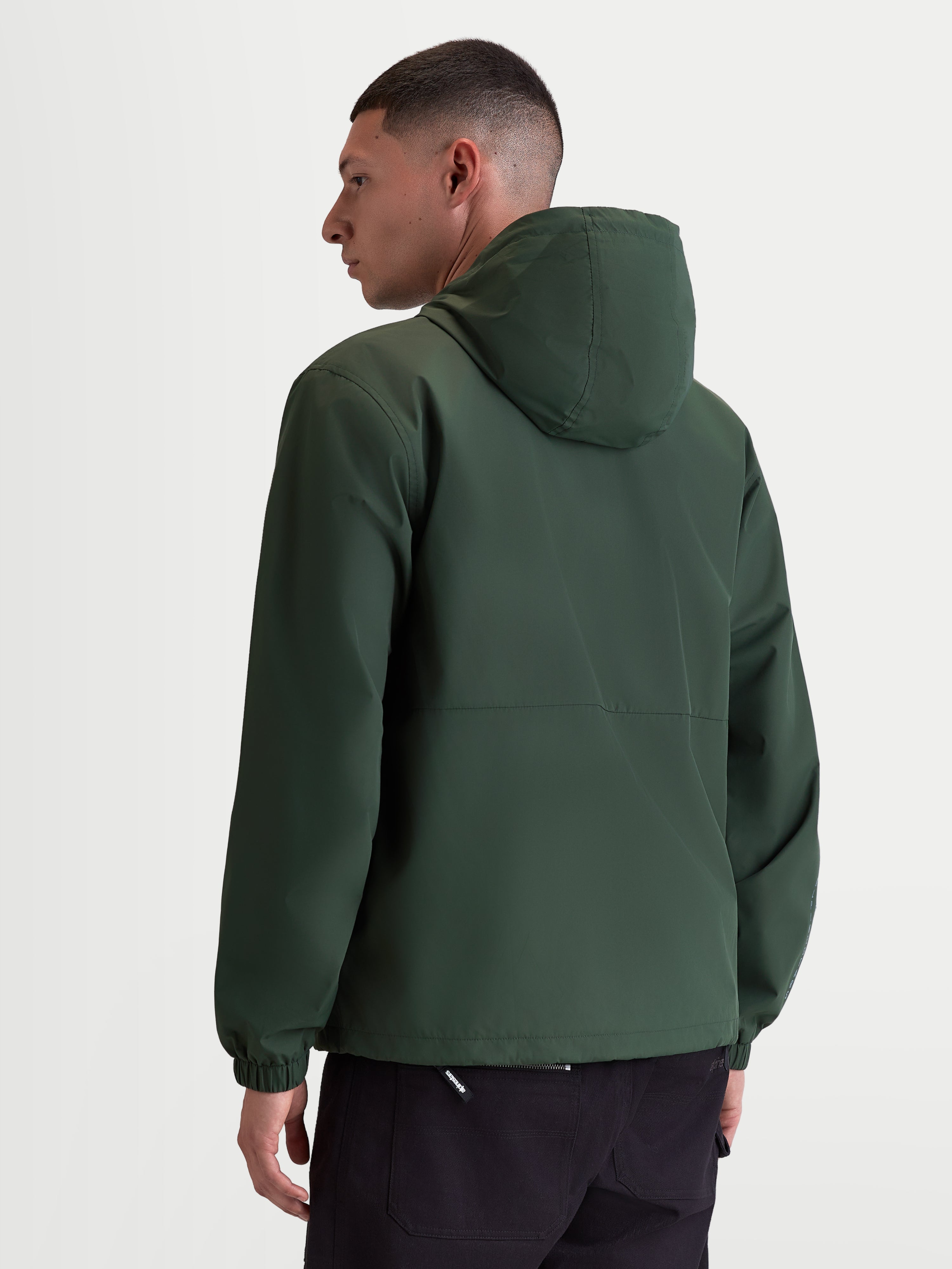 Alpinestars Speeder Resolve, casaco corta-vento de sportswear leve para uso urbano, verde, vista traseira num modelo realçando o design limpo das costas e os punhos elásticos, 100% poliéster com forro em malha.