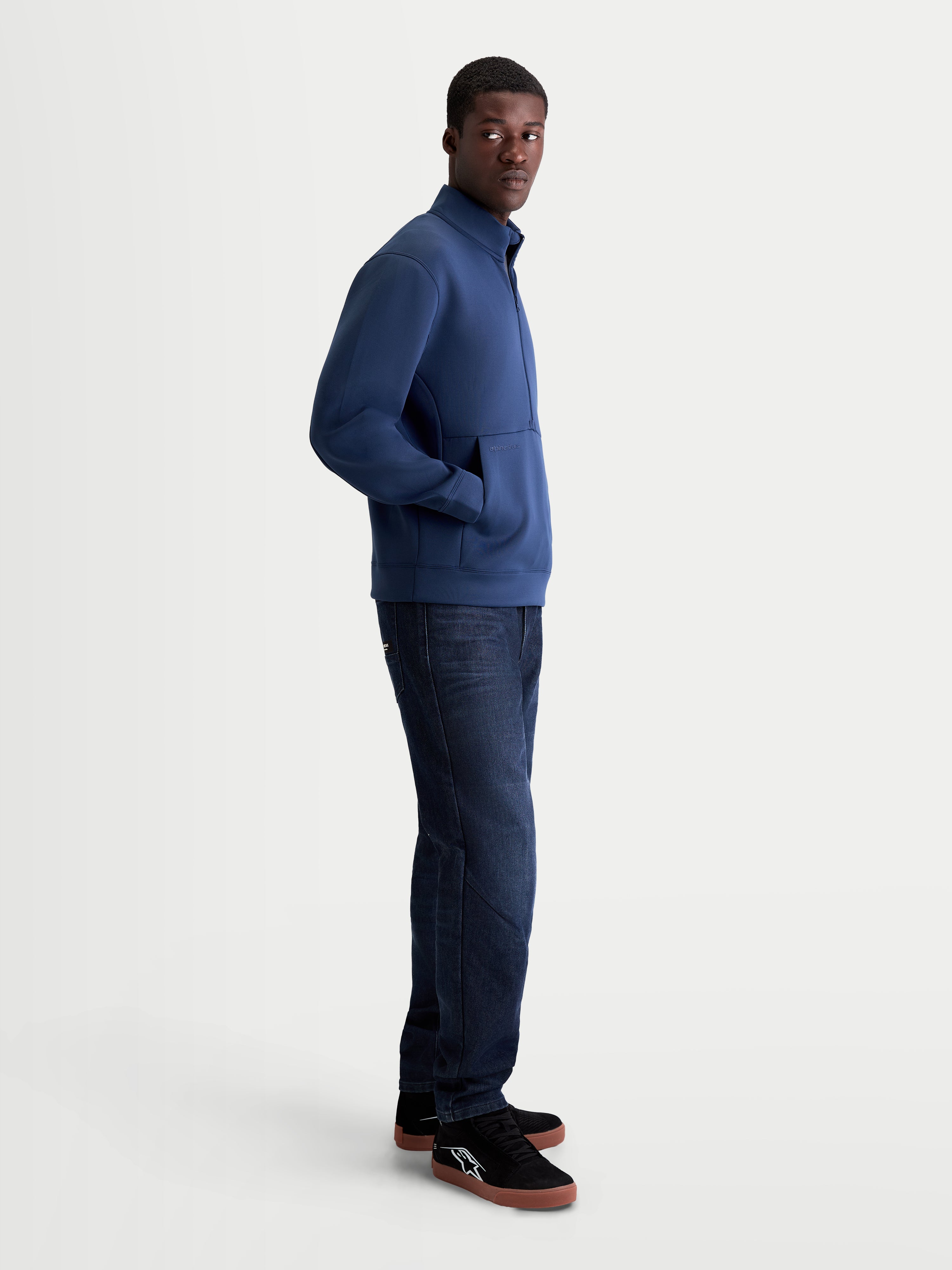 Alpinestars sweatshirt Apera Half-Zip, pullover de sportswear para homem, azul, fecho de meio fecho e bolso canguru, fleece tri-blend, estilo motorsport casual, vista lateral num modelo.