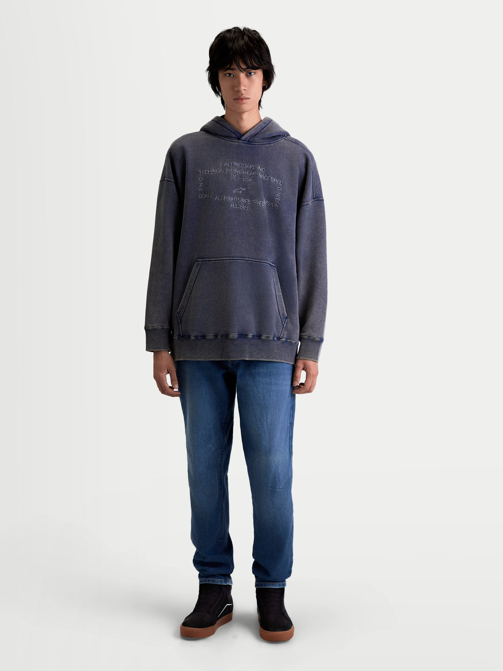 Alpinestars Camisola Com Capuz Infinite Washed Oversized, camisola casual de estilo sportswear vestida por um modelo, azul com acabamento snow-wash, bolso canguru frontal e logótipo Alpinestars bordado no peito, silhueta oversized e ajuste relaxado.
