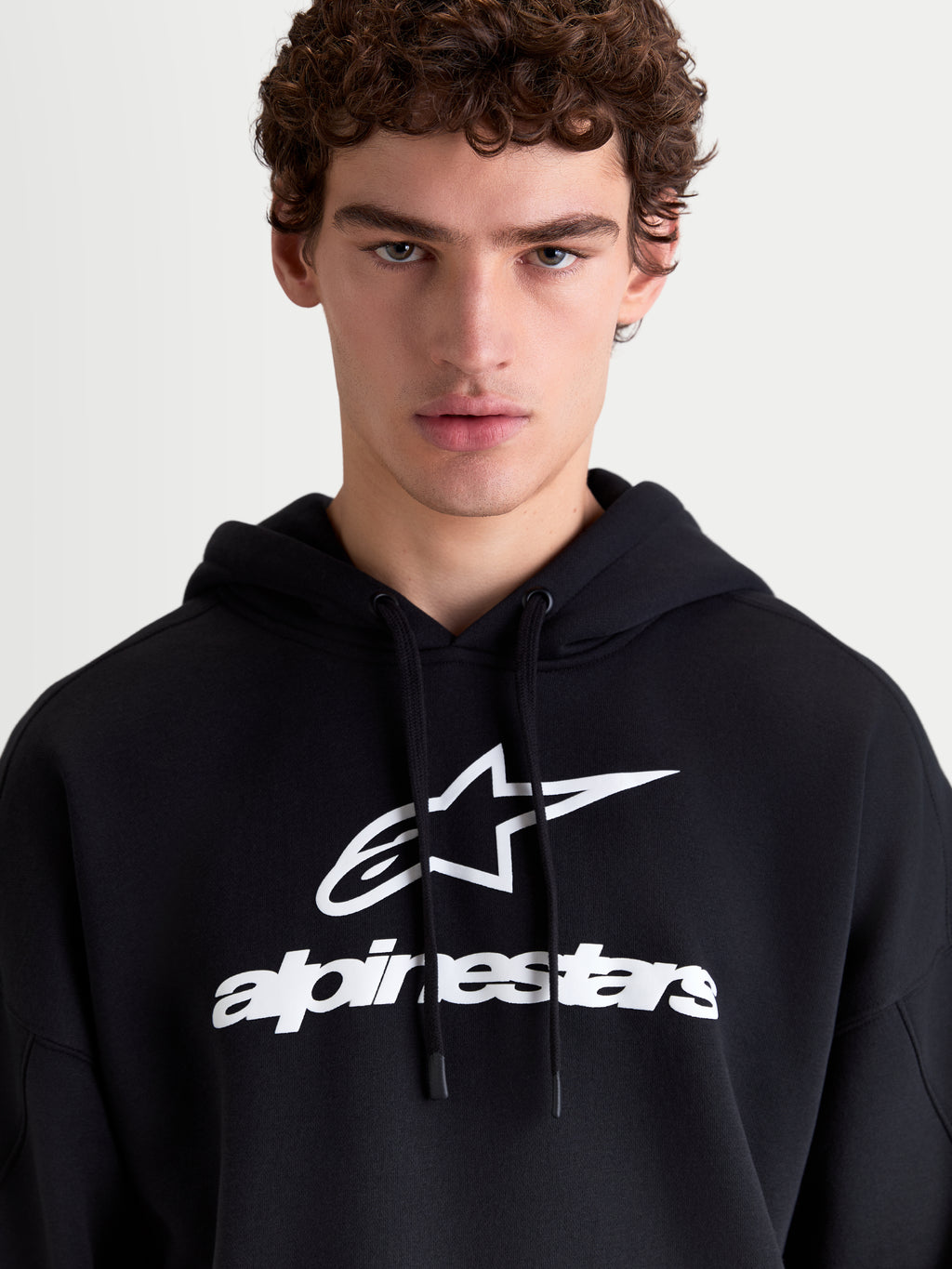 Alpinestars Camisola com Capuz Prelude Oversized, hoodie de sportswear em fleece para homem, preta e branca, com logótipo em relevo no peito e cordões planos, vista frontal no modelo.