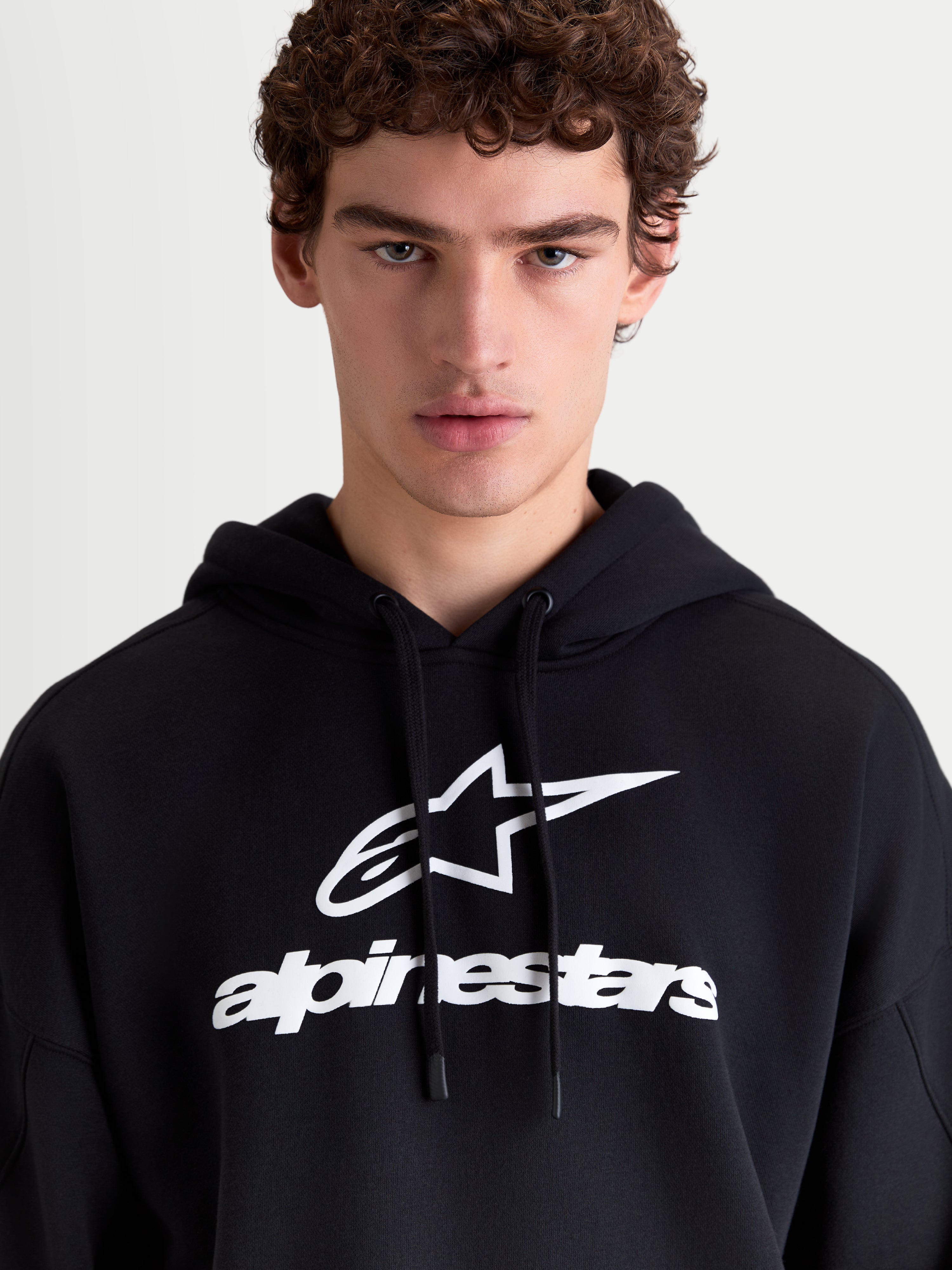 Alpinestars Camisola com Capuz Prelude Oversized, hoodie de sportswear em fleece para homem, preta e branca, com logótipo em relevo no peito e cordões planos, vista frontal no modelo.