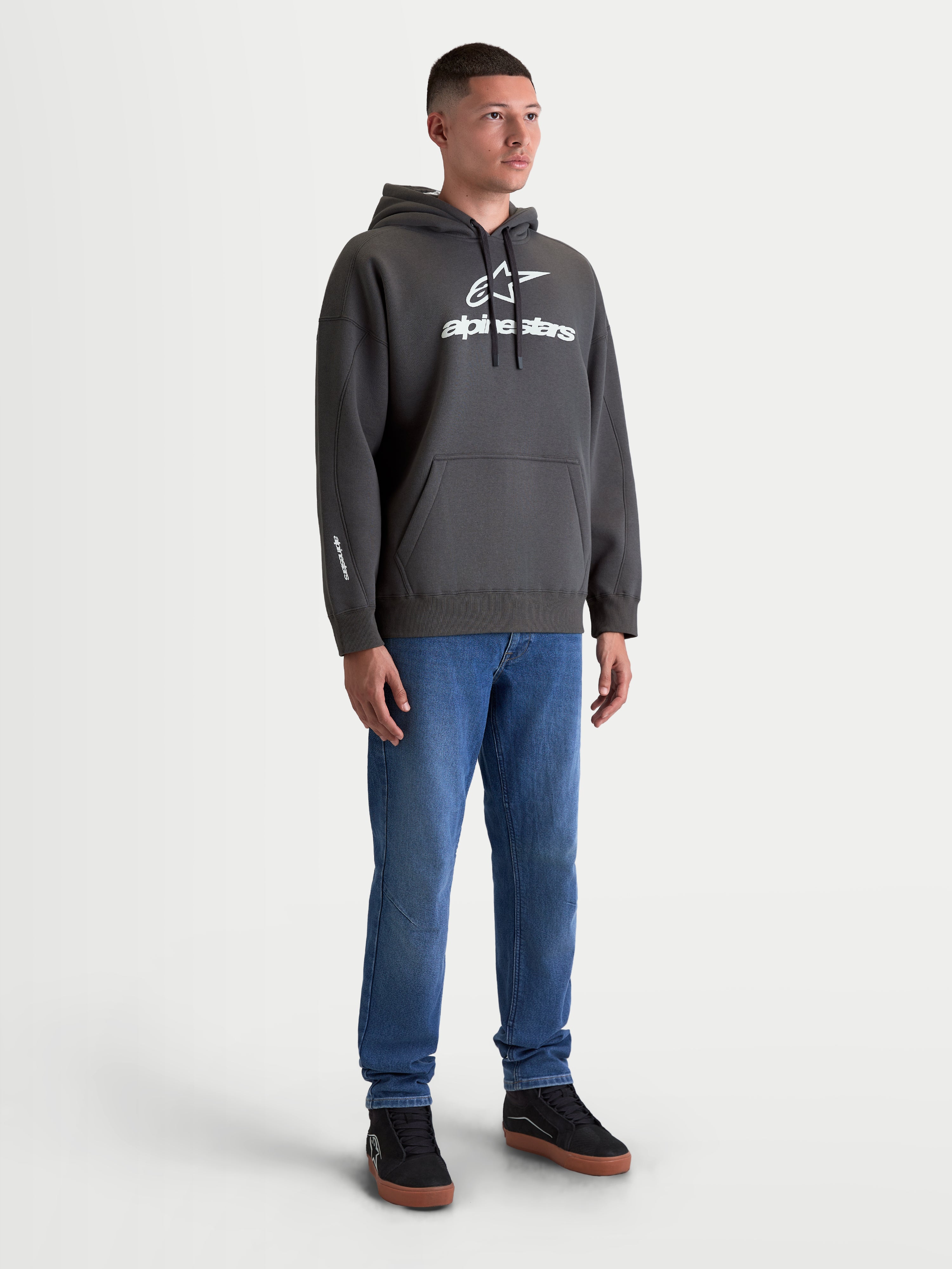 Alpinestars camisola com capuz Prelude Oversized, hoodie em fleece premium em cinzento charcoal, logótipo em relevo branco, bolso canguru e ajuste oversized, modelo masculino para um visual casual de sportswear.