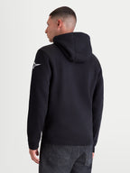 Alpinestars camisola com capuz Race Wordmark, casual sportswear para homem, preta e branca, vista traseira no modelo, logótipo Ageless branco na manga esquerda, punhos canelados, fleece de algodão e poliéster reciclado.