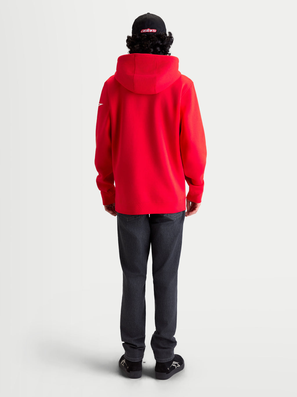 Alpinestars camisola com capuz Race Wordmark, camisola em fleece vermelha com detalhes brancos, vista traseira num modelo com capuz forrado e logótipo Ageless na manga, vestuário casual de motorsport.