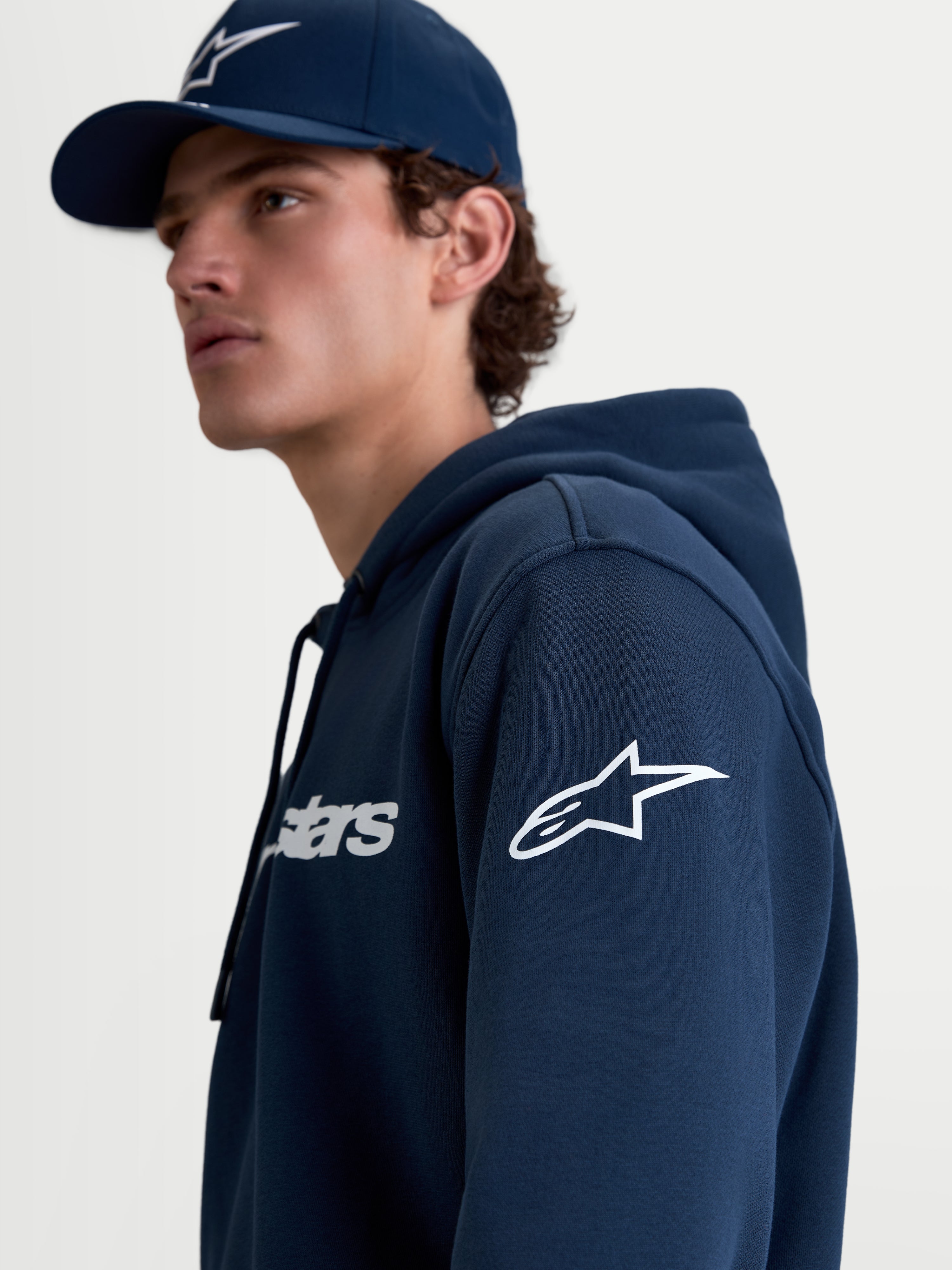 Alpinestars Camisola Com Capuz Race Wordmark, camisola de sportswear para homem em fleece, azul marinho e branca, com o logótipo Ageless na manga e logótipo Race no peito, vista de estilo de vida em modelo.