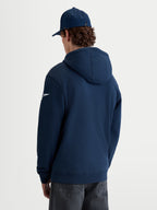Alpinestars Race Wordmark Hoodie, camisola com capuz em fleece para homem, azul marinho e branca, vista traseira em modelo com logótipo Ageless branco na manga e capuz forrado do mesmo tecido.