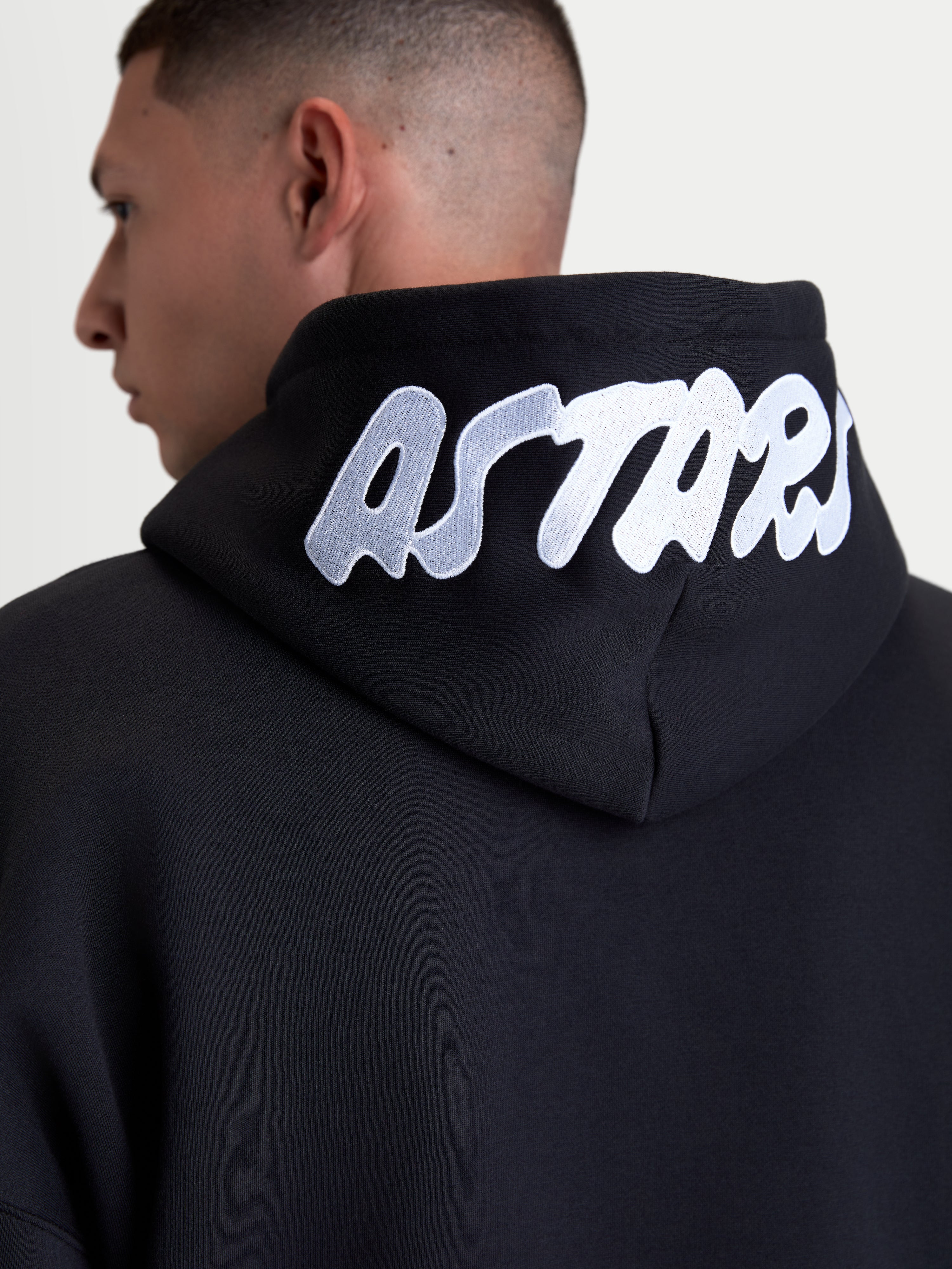 Alpinestars camisola com capuz Pioneer Oversized, fleece casual sportswear com fecho, preta com logótipo ASTARS bordado a branco no capuz, vista traseira em detalhe, construção em mistura de algodão premium.