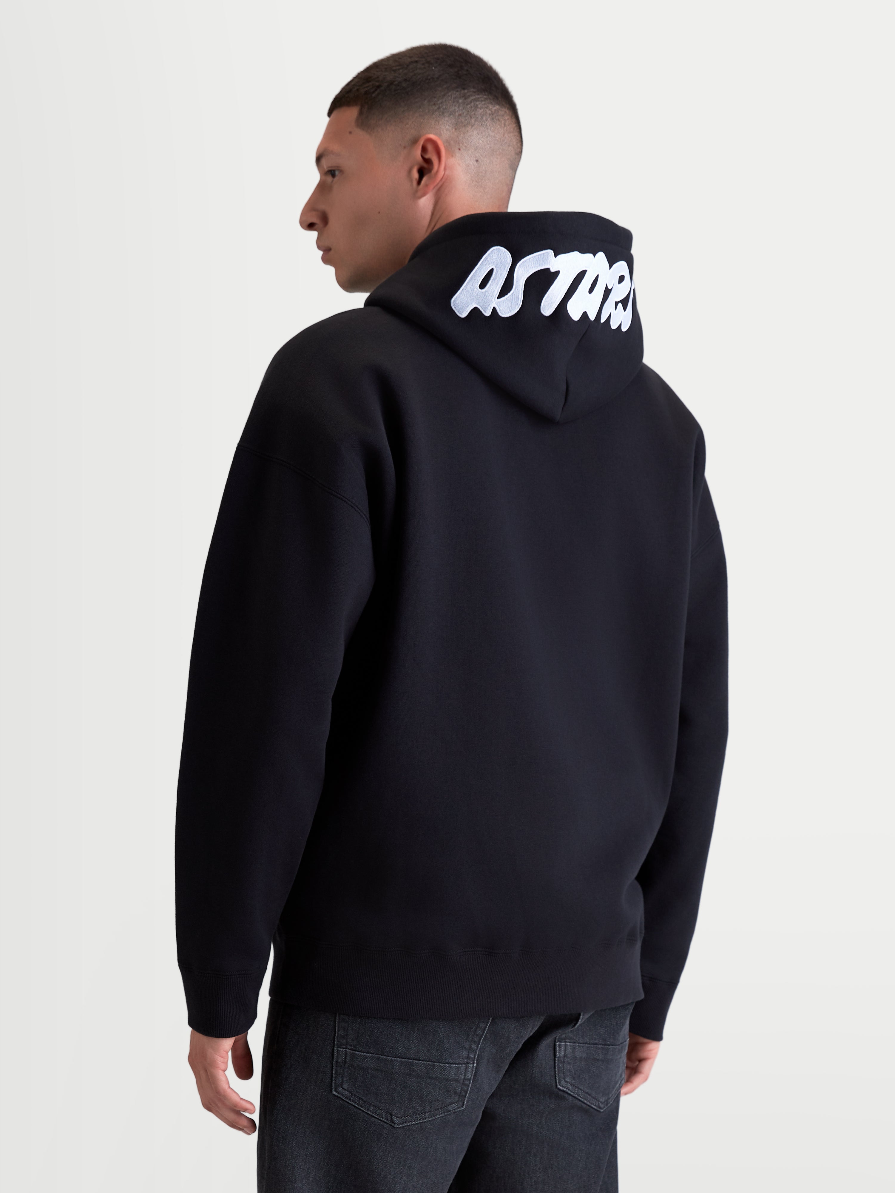 Alpinestars camisola com capuz Pioneer Oversized, hoodie sportswear para homem, preta e branca, corte oversized, com logótipo ASTARS branco bordado no capuz, construção em fleece premium, vista traseira num modelo.