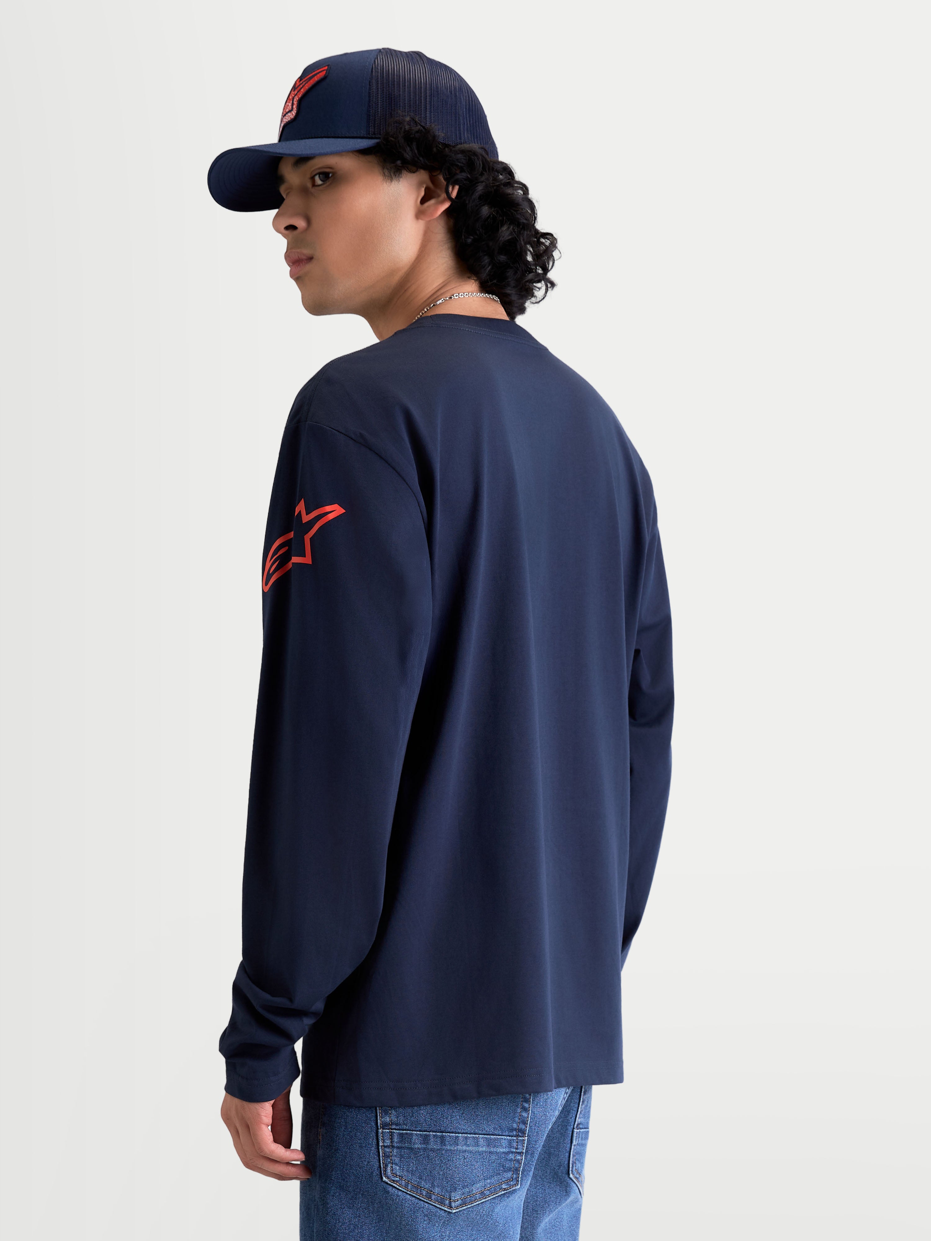 Alpinestars Velocifier CSF T-shirt, t-shirt de manga comprida sportswear, azul-marinho e vermelha, vista traseira em modelo com logótipo Astars vermelho no ombro e punhos canelados, construção em 80% algodão e 20% poliéster reciclado.