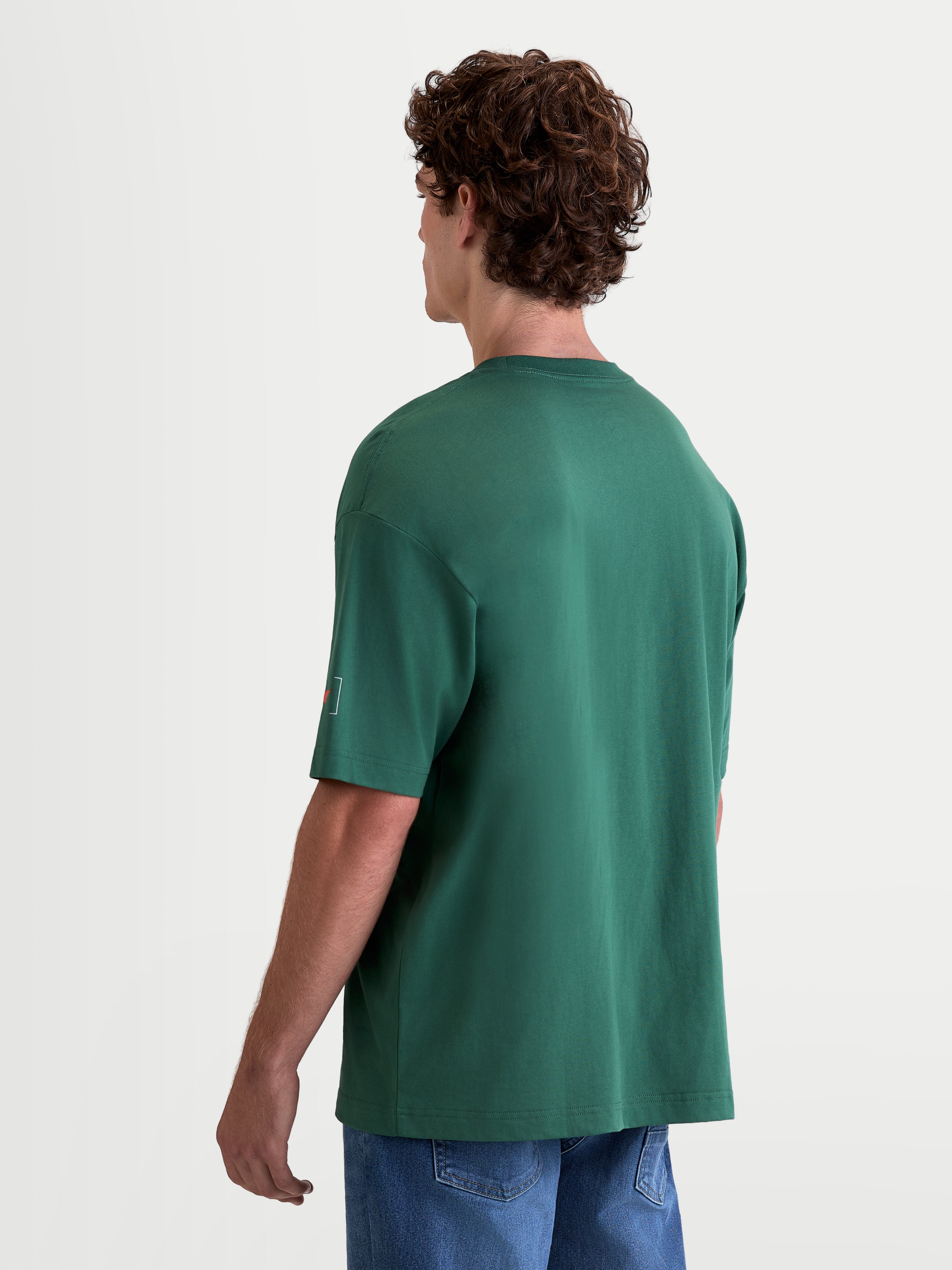 Alpinestars Infinity Oversized CSF Tee, Men's Short Sleeve Sportswear T-Shirt, Green, features an oversized fit and cotton-poly blend construction, back view on model showing sleeve logo detailing.