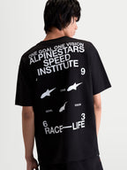 Alpinestars T-Shirt Institute Oversized CSF, t-shirt de manga curta, preta e branca, vista traseira em modelo com gráficos Alpinestars Speed Institute e Race-Life nas costas, corte oversized descontraído, sportswear inspirado no motorsport.