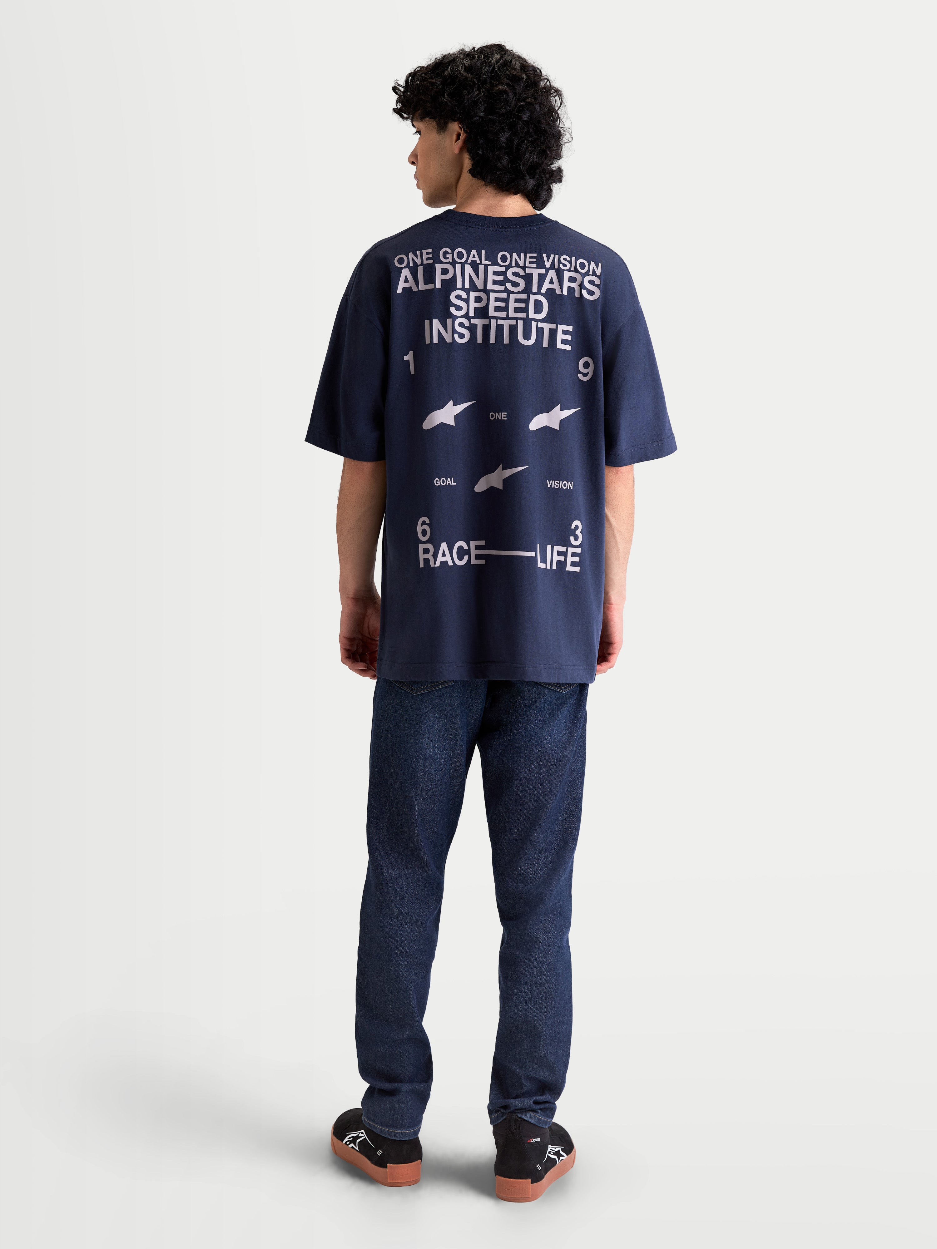 Alpinestars Institute Oversized CSF Tee, t-shirt de manga curta azul-marinho, vista traseira no modelo com grafismo branco grande Alpinestars Speed Institute, slogan One Goal One Vision e branding Race Life, corte oversized descontraído, casual sportswear.