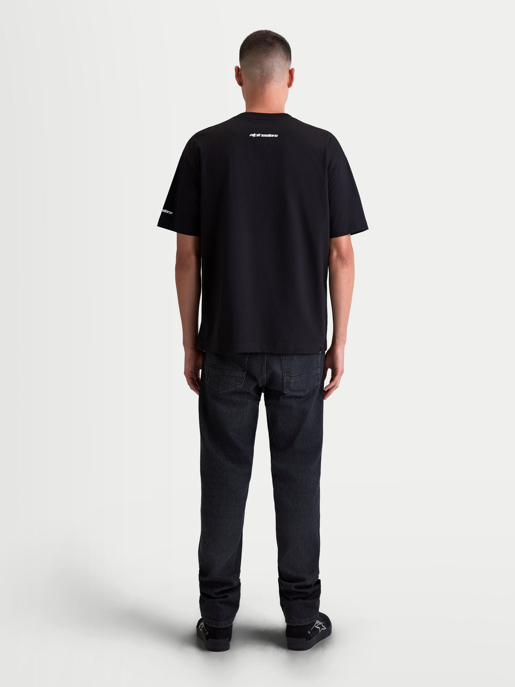 Alpinestars T-shirt Mandate Oversized CSF, t-shirt de manga curta unissexo, preta, vista traseira no modelo com gráficos brancos em puff print no pescoço e na manga, corte oversized descontraído, sportswear.