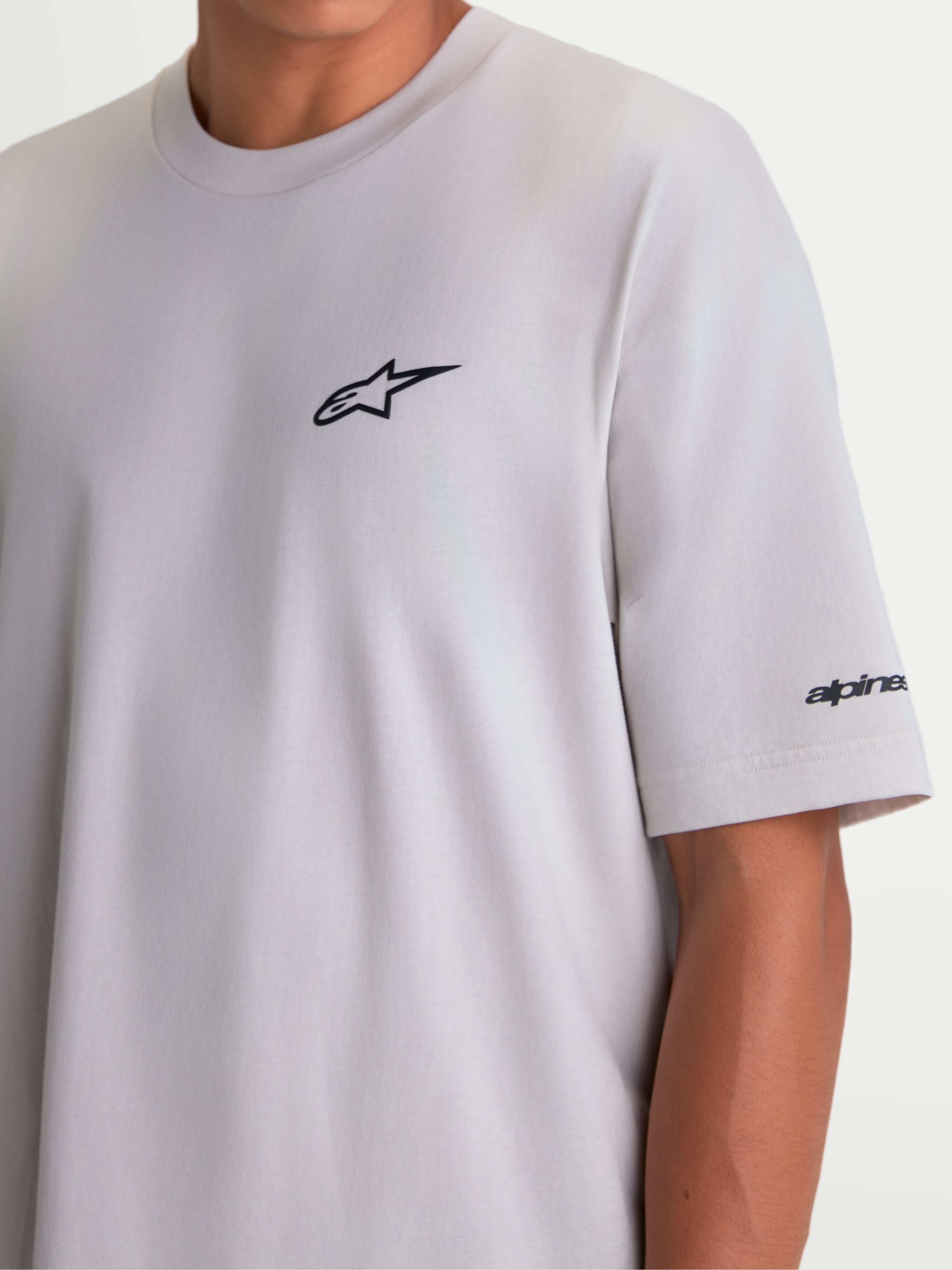 Alpinestars T-shirt Mandate Oversized CSF, t-shirt de manga curta unissexo, cinzenta, com logótipo Astars preto em puff print no peito e pormenor gráfico na manga, corte oversized para conforto casual, sportswear