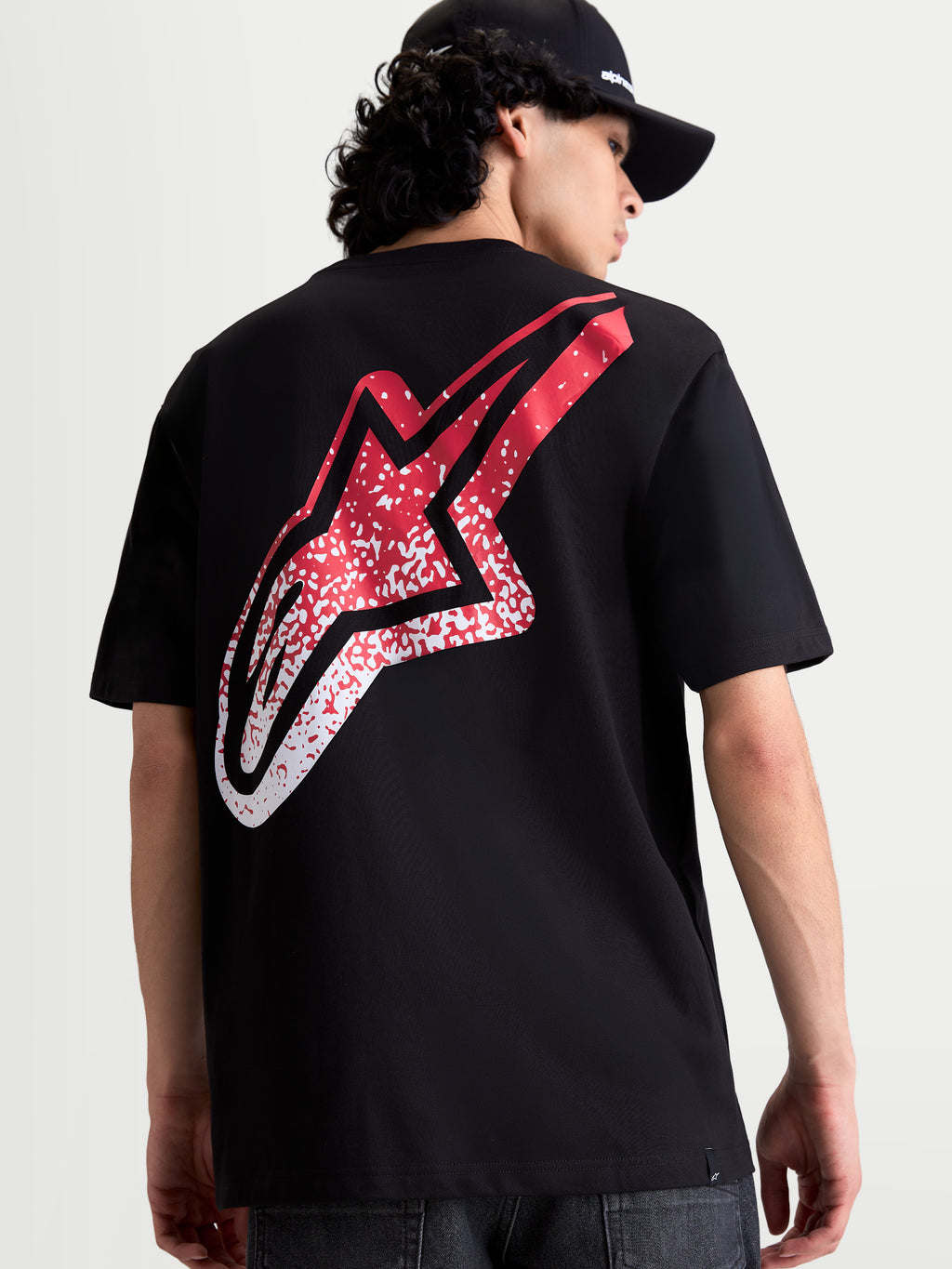 Alpinestars Meteor CSF, t-shirt de manga curta preta, vista traseira no modelo com grande logótipo Astars em gradação vermelho e branco, sportswear casual de motorsport.