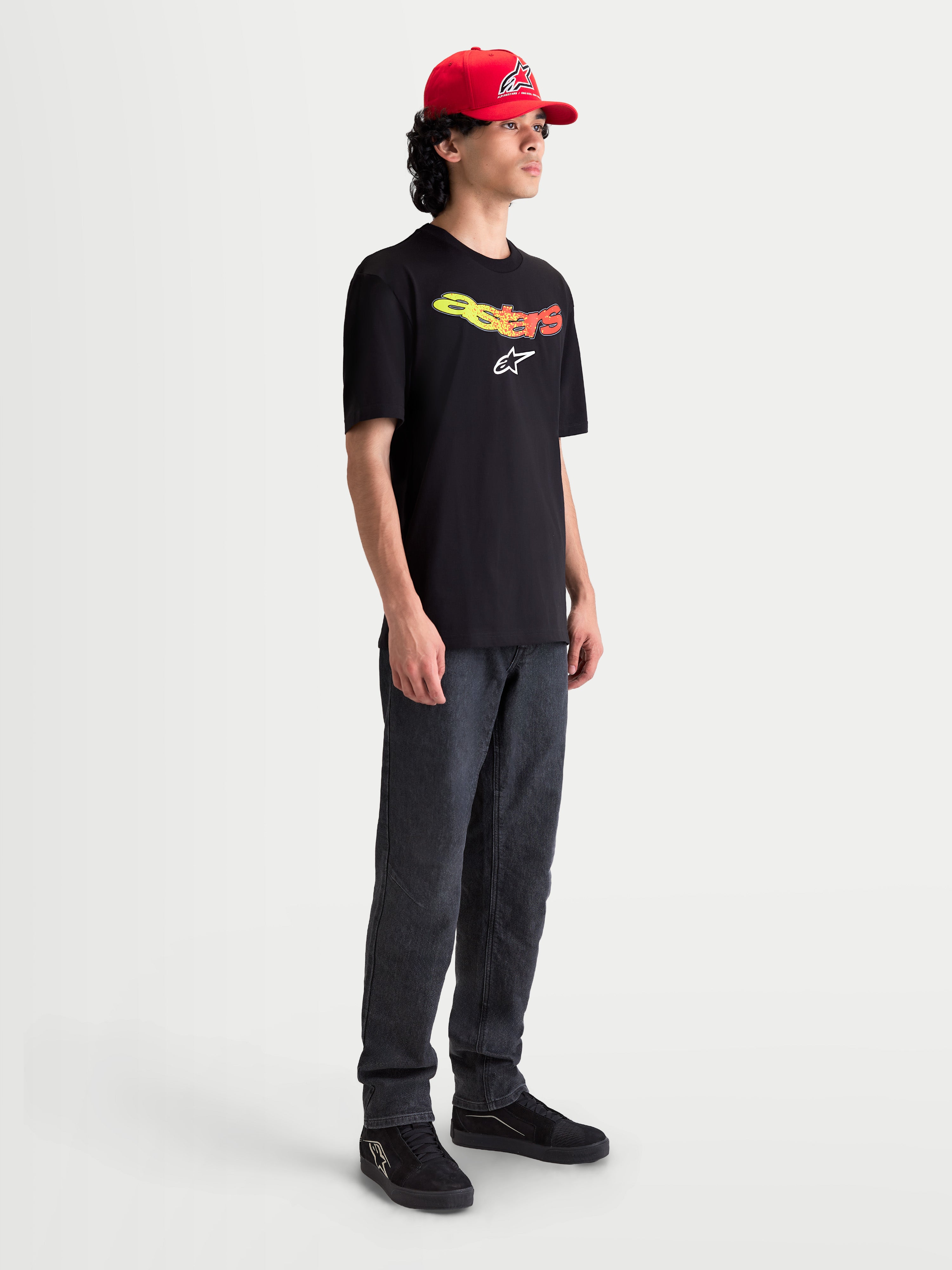 Alpinestars T-shirt Elliptogrit CSF, t-shirt de manga curta para homem, preta com lettering Astars em gradiente amarelo e vermelho e logótipo branco, casual sportswear, modelo a usar a t-shirt.
