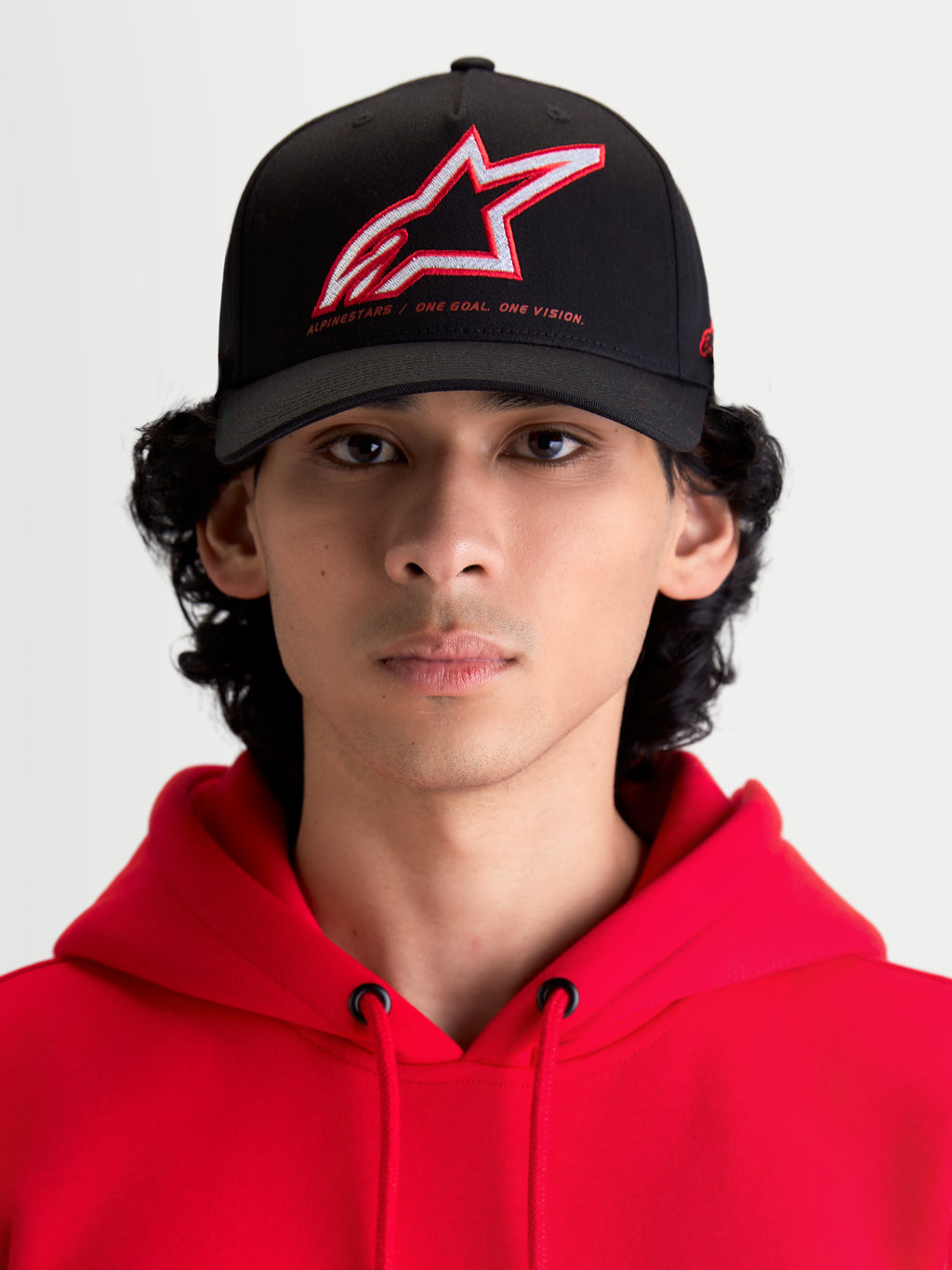 Alpinestars Boné Lineout, boné de basebol unissexo, preto com logótipo Astars bordado a vermelho e branco, inscrição One Goal One Vision, aba curva e construção estruturada em sarja, modelo com casaco com capuz vermelho.