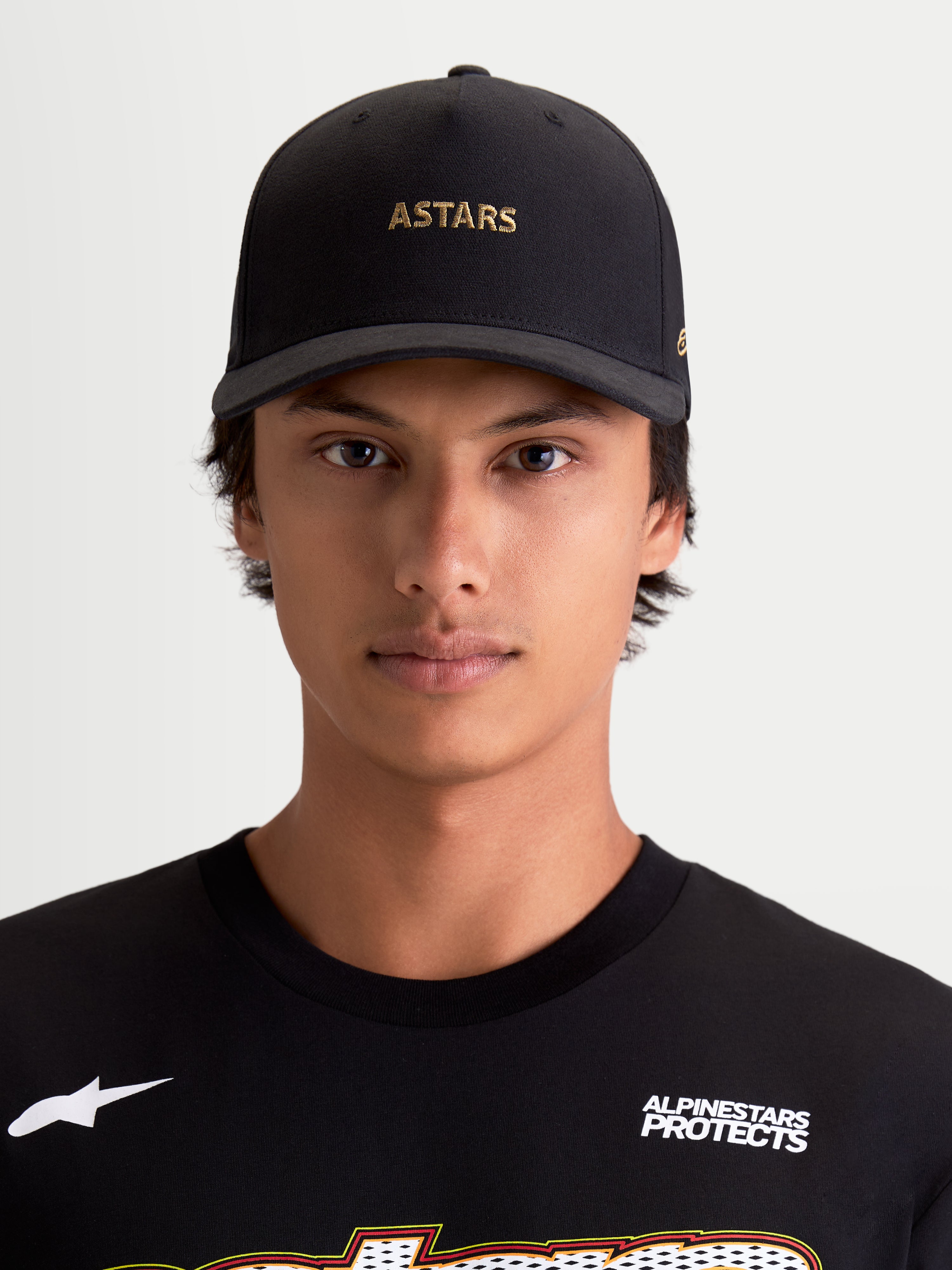 Alpinestars Chapéu County Canvas, boné de pala curva para sportswear, preto com bordado do logótipo ASTARS em dourado, tecido oxford peached e copa estruturada, estilo casual visto num modelo.