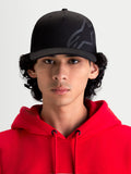 Alpinestars chapéu Maze, boné de sportswear inspirado no motorsport, preto, vista frontal num modelo a usar uma camisola com capuz vermelha, com coroa estruturada, aba curva e logótipo Astars Corp Shift texturizado em tecido de sarja durável para um estilo casual fora da moto.