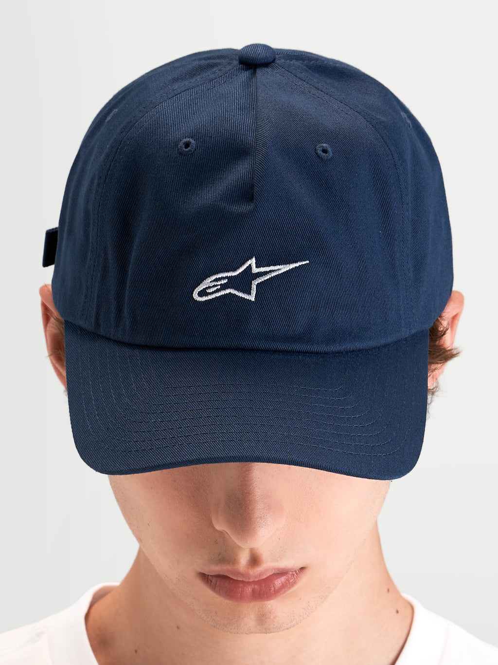 Alpinestars Boné Dad Dylan, boné desportivo casual usado por um modelo, azul com aba curva e logótipo Astars branco bordado na frente